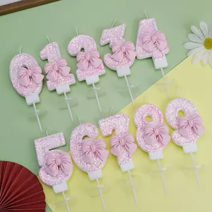 Vista detallada de velas de cumpleaños con números de purpurina rosa y lazo decorativo