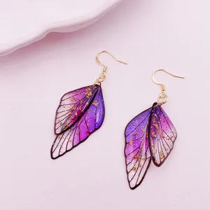 Close-up of elegant purple gradient cicada wing earrings with gold glitter detail