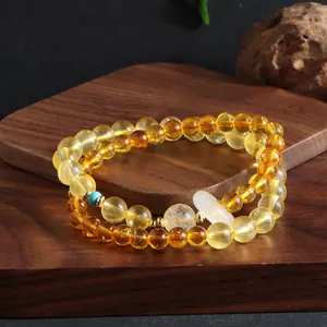 Detail of a citrine double-loop bracelet with a white running ring charm and turquoise accent.