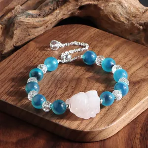 Detailaufnahme eines Armbands mit blauen Achatperlen und einer geschnitzten Katze.