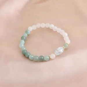 Detaillierte Makroansicht eines Perlenarmbands aus grünem Achat und rosa Kristall auf Satin