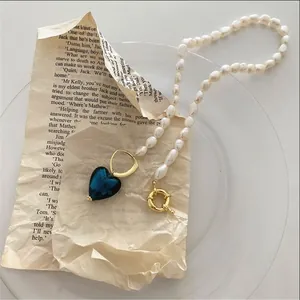 Vista dettagliata di una collana di perle barocche con pendente a cuore in vetro blu vintage