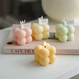 Detalle de velas perfumadas en forma de cubo de colores pastel colocadas sobre un libro