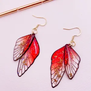 Detailed macro view of elegant red gradient cicada wing earrings with golden foil flakes