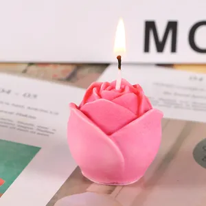 Primer plano de una vela perfumada rosa con forma de rosa y una llama cálida y estable
