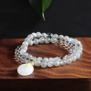 Close-up of double-wrap moonstone and white crystal bracelet with pendant on wood