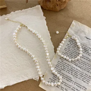 Detail view of a baroque natural pearl necklace and bracelet set on vintage paper.