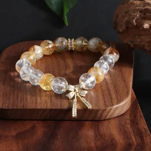 Nahaufnahme eines Armbands aus Citrin- und Bergkristall mit goldenem Schleifenanhänger.