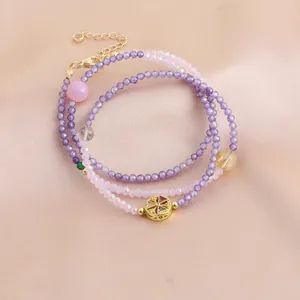 Vue détaillée du bracelet en perles de cristal violet et rose avec breloque dorée