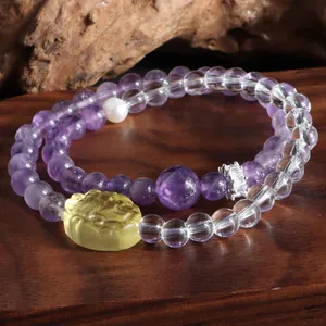 Détail macro des perles d'améthyste et de quartz avec une breloque lion sculptée