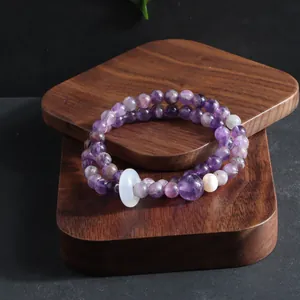Macro view of a double-strand amethyst bracelet with a white pi disc charm and a pearl