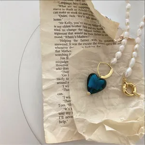 Dettaglio collana vintage con perle barocche, ciondolo a cuore blu e chiusura dorata