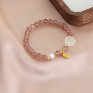 Detailed macro view of an elegant strawberry quartz beaded bracelet with a pearl and cat paw charm