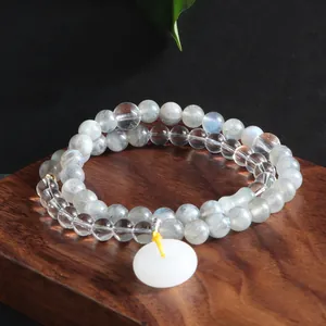 Close-up of double-strand grey moonstone and clear quartz bracelet with white donut charm