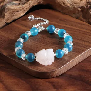 Nahaufnahme von blauem Achat und Kristallarmband mit einem rosa geschnitzten Anhänger