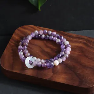 Close-up detail of natural amethyst multi-strand crystal bracelet on dark wooden display