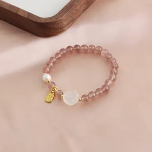 Exquisite close-up of natural strawberry quartz beaded bracelet with pearl and gold lucky charm