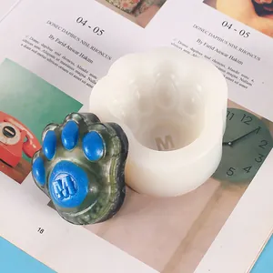 Detailed close-up showing a white cat paw silicone mold and a finished blue resin paw with M logo