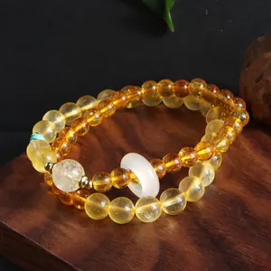 Detail of double-layer yellow quartz beaded bracelet with a white agate ring charm.