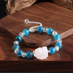 Detailansicht eines blauen Achat-Armbands mit Bergkristall und geschnitztem Pixiu-Anhänger.