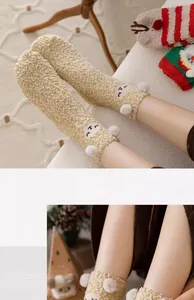 Nahaufnahme dicker Korallenfleece-Socken mit Tierstickerei und Pompons für Weihnachten.