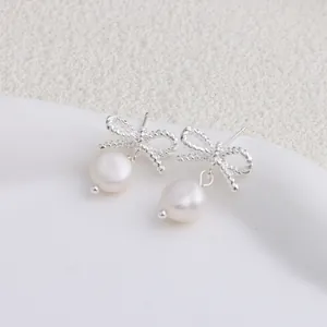 Dettaglio ravvicinato di orecchini a fiocco in argento con eleganti perle d'acqua dolce