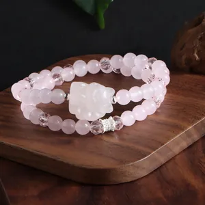 Gros plan d'un bracelet double en quartz rose avec une breloque renard sculptée et des perles