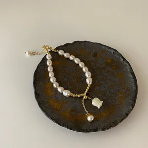 Detailaufnahme einer Süßwasserperlen-Halskette mit einer zarten Muschelblume auf einem Teller.