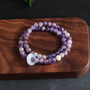Close-up detail of natural amethyst multi-wrap bracelet featuring white donut bead on wood