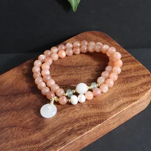 Detailansicht eines eleganten, zweireihigen Natursonnenstein-Armbands mit weißem Jade-Anhänger