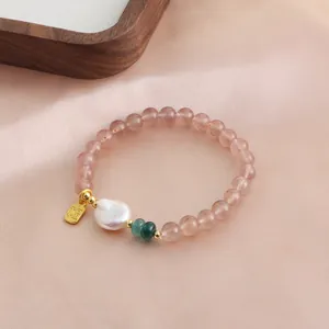 Close-up of natural strawberry quartz beaded bracelet with a gold Fu charm and pearl