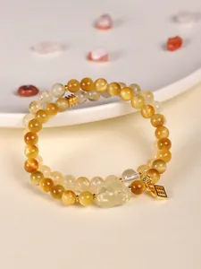 Detailed macro view of yellow tiger eye beads and citrine bracelet with carved pixiu charm.
