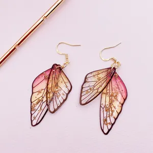 Artistic handmade cicada wing earrings with a pink gradient and shimmering gold foil