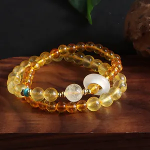 Detailed macro shot of a citrine double-strand bracelet with a white jade donut charm.
