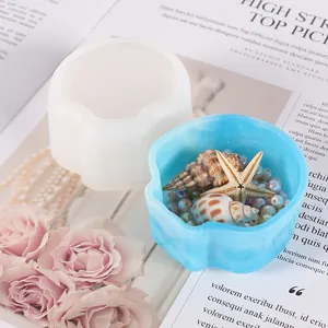 Siliconen mal in bloemvorm en afgewerkt blauw harsbakje met zeeschelpen en kralen.
