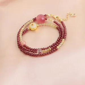 Gros plan d'un bracelet en perles de grenat multicouche sur fond de soie rose élégant