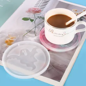 Close-up of a ghost-shaped silicone mold next to a finished marble-effect coaster.