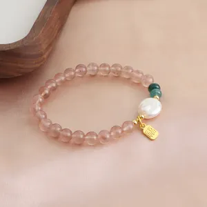 Close-up of strawberry crystal beaded bracelet with pearl and golden Fu charm