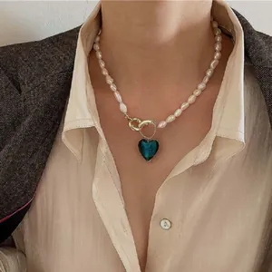 Primo piano di una collana di perle barocche retrò con un ciondolo a cuore blu