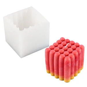 Detailed view of a silicone mold with its finished 3D cube-shaped red decorative candle