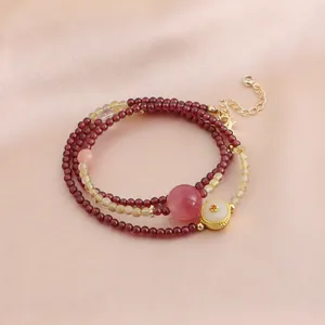 Vue détaillée d'un bracelet de perles en grenat à trois rangs sur satin rose élégant