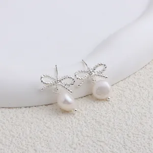 Primo piano di orecchini a fiocco in argento con perle bianche naturali d'acqua dolce.