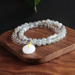 Close-up of double-strand grey moonstone and clear quartz bracelet with jade donut