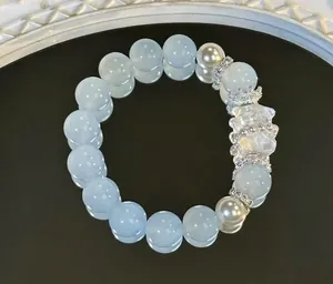 Nahaufnahme von elegantem hellblauem Kristall- und Perlenarmband mit transparentem Bärenanhänger