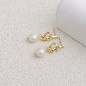 Primo piano di orecchini a nodo d'oro con perle naturali d'acqua dolce su bianco