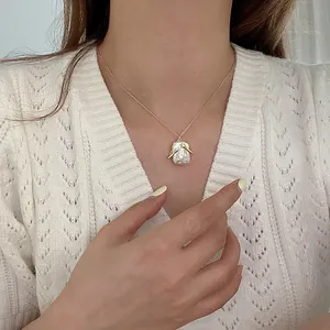 Macro di un'elegante collana con pendente in perla barocca e dettagli braccia dorate