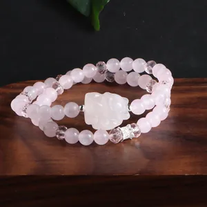 Gros plan d'un bracelet double rang en quartz rose naturel avec un charm renard sculpté