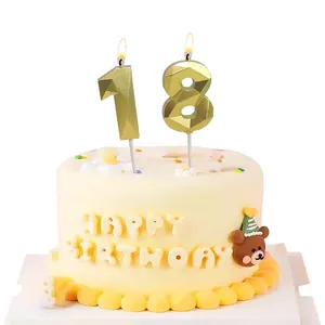 Detalle de las velas doradas número 18 facetadas sobre una tarta de cumpleaños