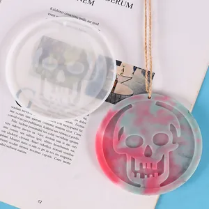 Detail view of skull silicone mold and a finished red and blue marble resin pendant.