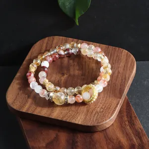 Detailed view of natural red phantom and citrine crystal multi-layer bracelet on wood
